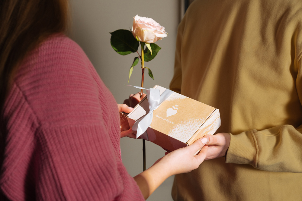 Eine Frau und ein Mann Halten eine Box und eine Rose als Geschenk Valentinstag in ihren Händen