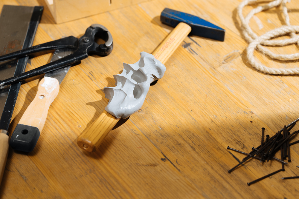 Verschiedene Werkzeuge liegen um einen Hammer mit einem Handabdruck am Griff. So wird er zum Geschenk zum Vatertag.